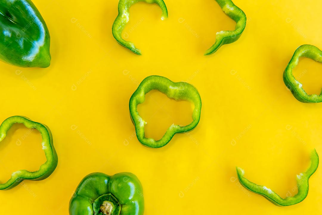 Pimentões verdes fatiados em fundo amarelo.