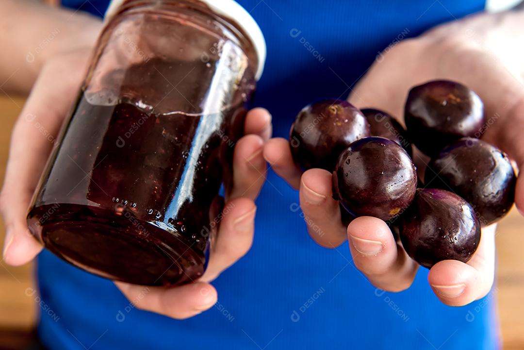 Mãos segurando geleia de jabuticaba orgânica caseira com exótica Braz