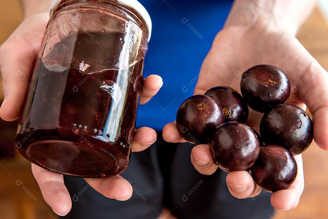 Mãos segurando geleia de jabuticaba orgânica caseira com exótica Braz