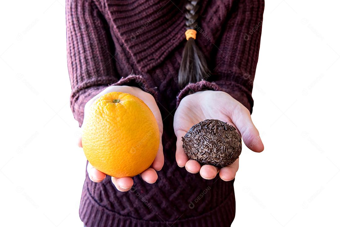 Garota segurando brigadeiro e uma laranja.