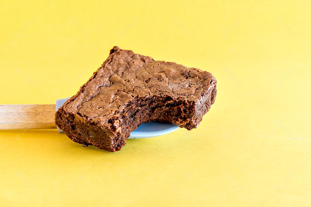 Brownie de chocolate caseiro em fundo amarelo.
