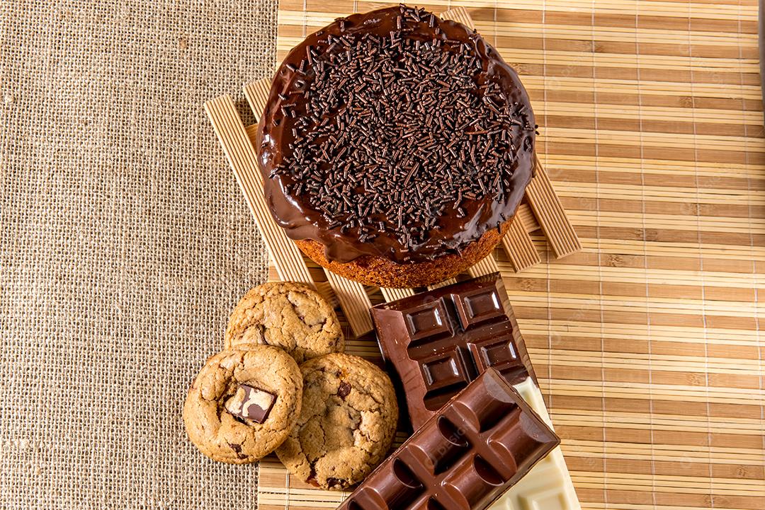 Doces na mesa. Bolo de chocolate, biscoitos e barra de chocolate.