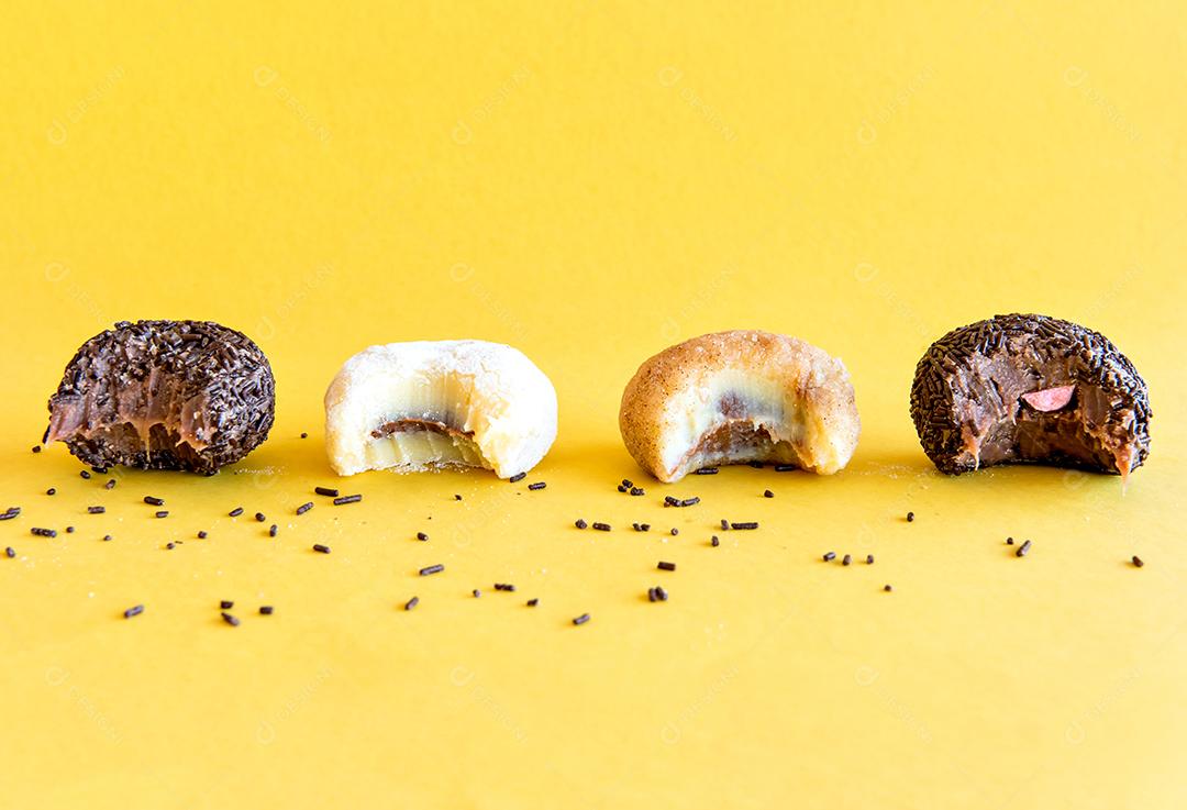 Brigadeiro de chocolate e doces em fundo amarelo.