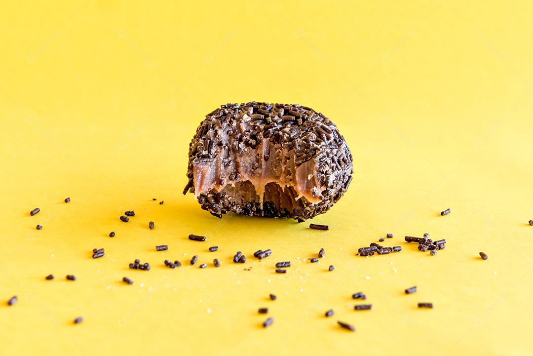 Brigadeiro de chocolate em fundo amarelo.