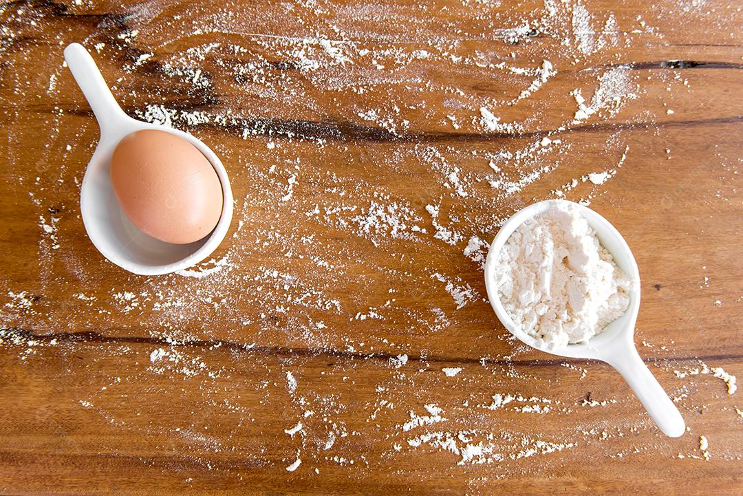 Ovo e farinha na mesa de madeira.