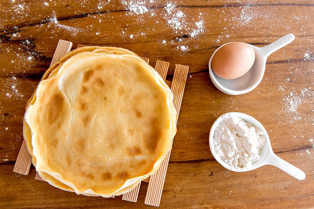 Ovo, panqueca e farinha na mesa de madeira