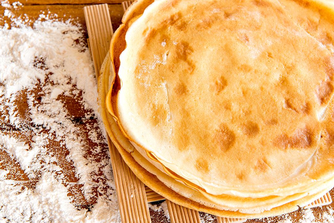 Panquecas em uma mesa com farinha espalhada.