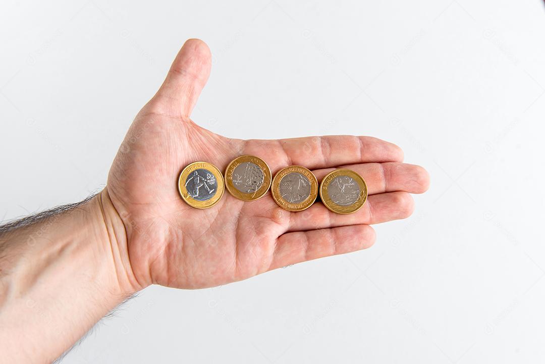Mão segurando moedas comemorativas brasileiras, moedas reais brasileiras