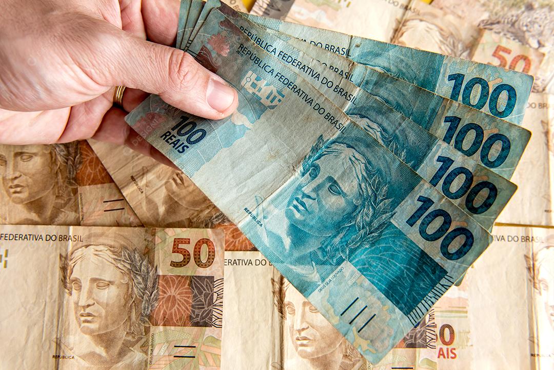 Mão segurando dinheiro brasileiro, notas brasileiras de 50 reais e Brazi