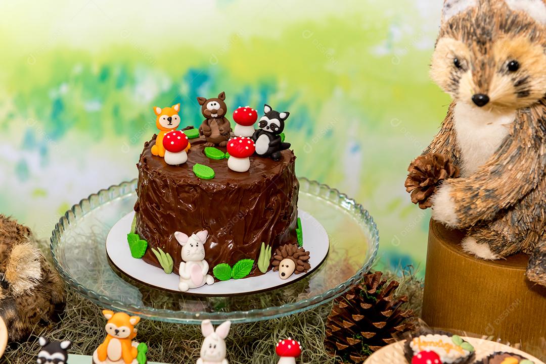 Mesa com bolo de chocolate para festa infantil.