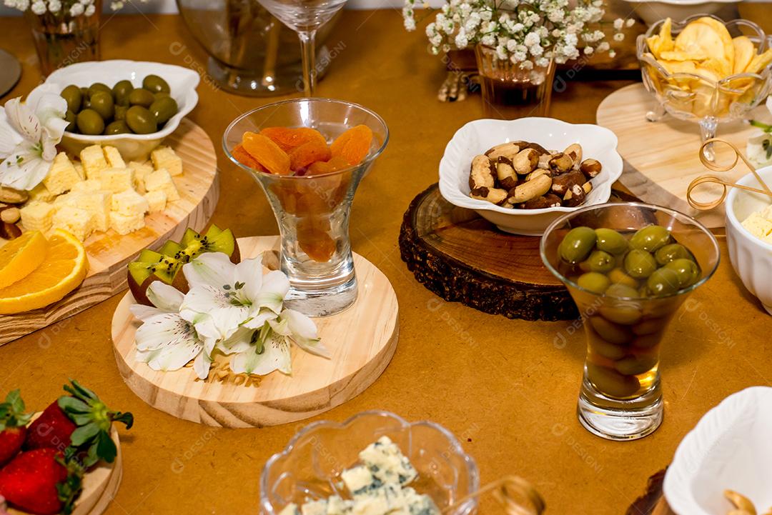 Mesa com comida, damasco, azeitona, castanha e queijo.