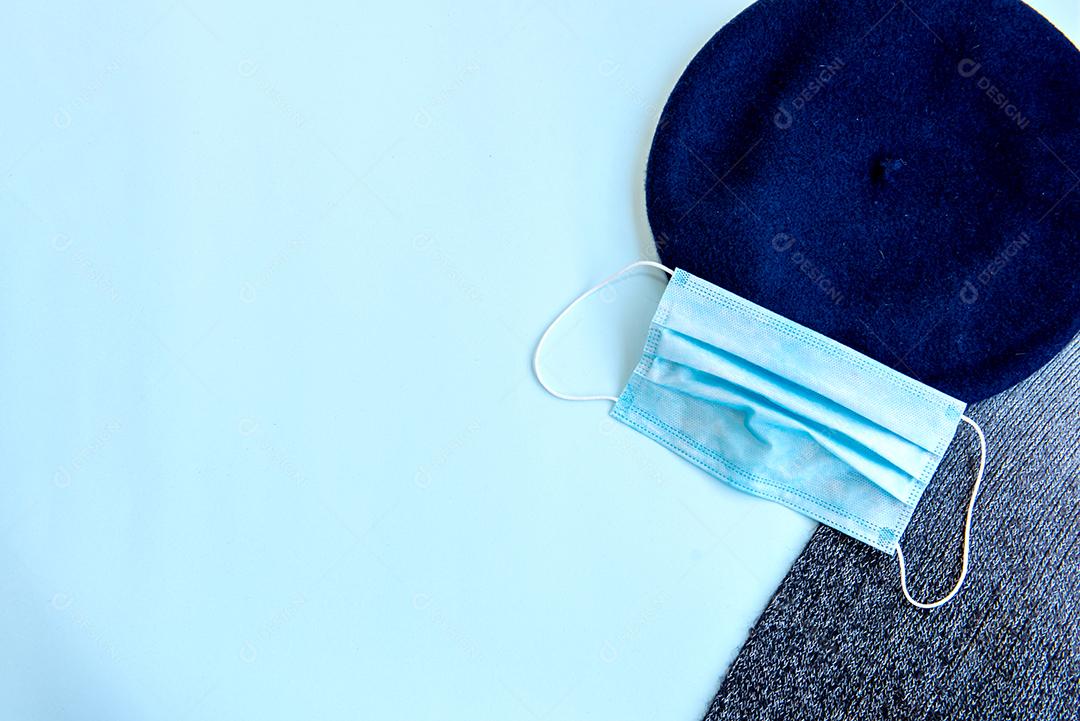 Boina, máscara e cachecol sobre fundo azul. Vista do topo.