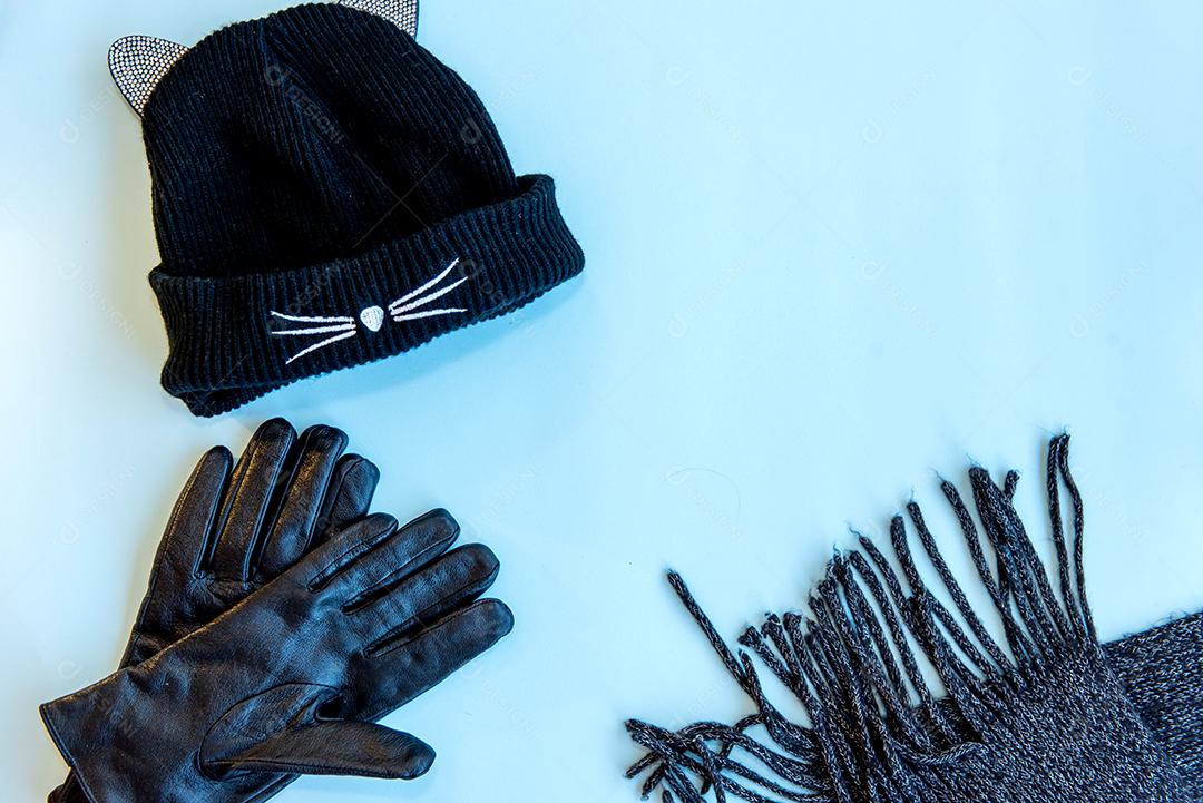 Boné, luva e cachecol sobre fundo azul. Vista do topo.