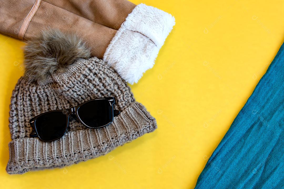 Boné, óculos escuros e jaqueta em fundo amarelo. Vista do topo.