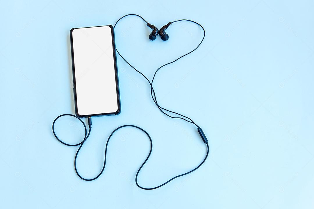 Fones de ouvido e smarthphone em fundo azul. Vista do topo.