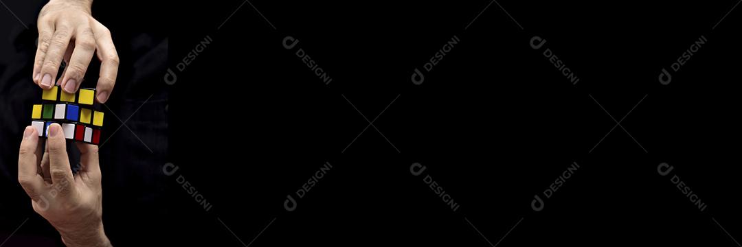 Mãos pessoas segurando cubo magico sobre fundo preto