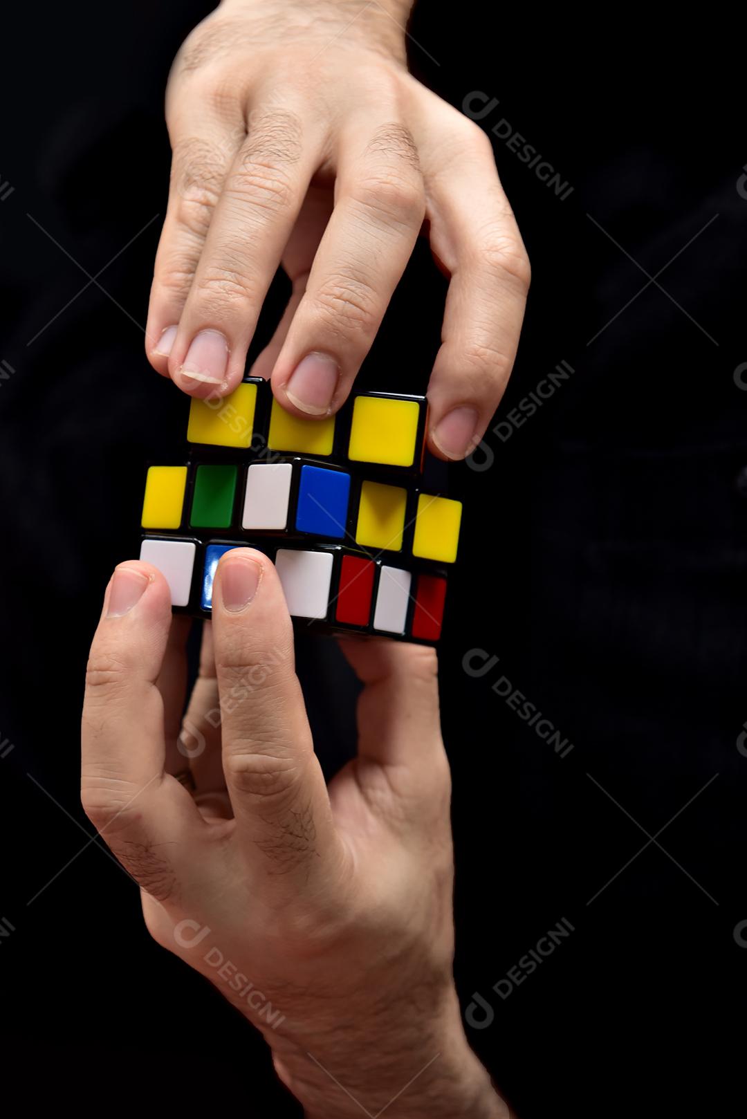 Menino sentado no sofá tentando montar o cubo mágico.