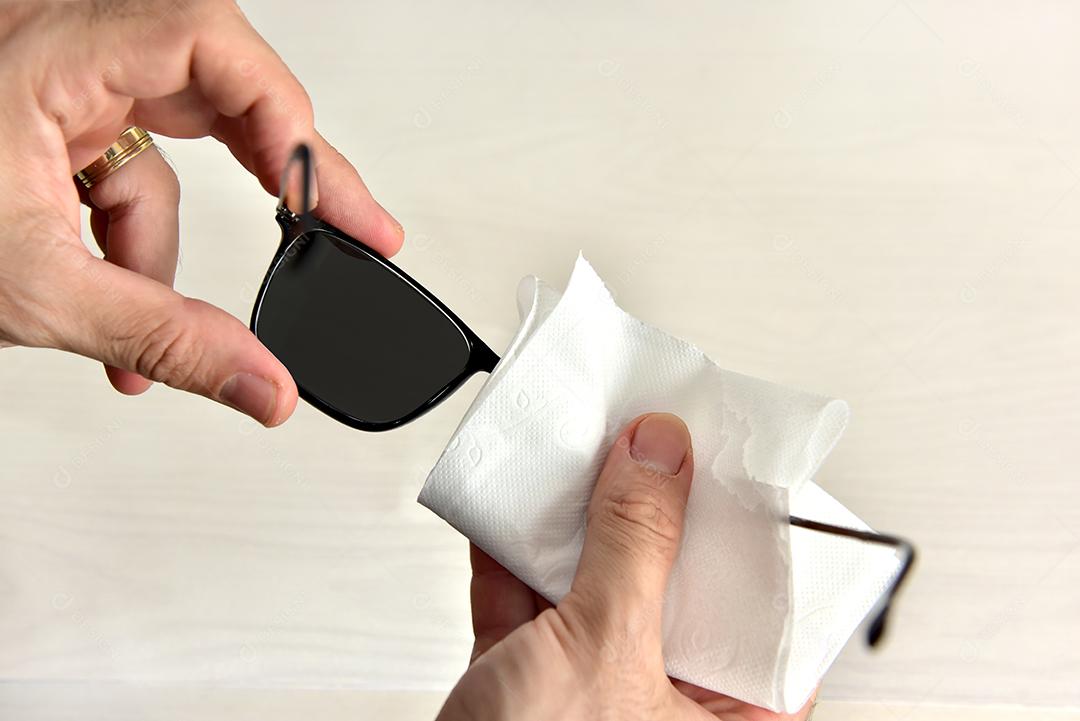 Mãos de pessoas limpando óculos lenço