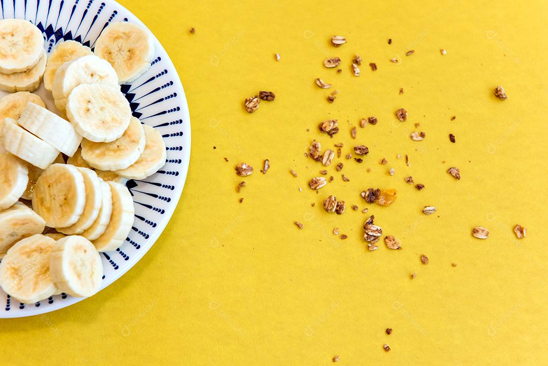 Prato com bananas fatiadas e granola. Vista do topo.