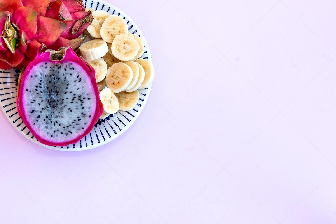 Prato com banana fatiada e pitaya cortada ao meio. Vista do topo