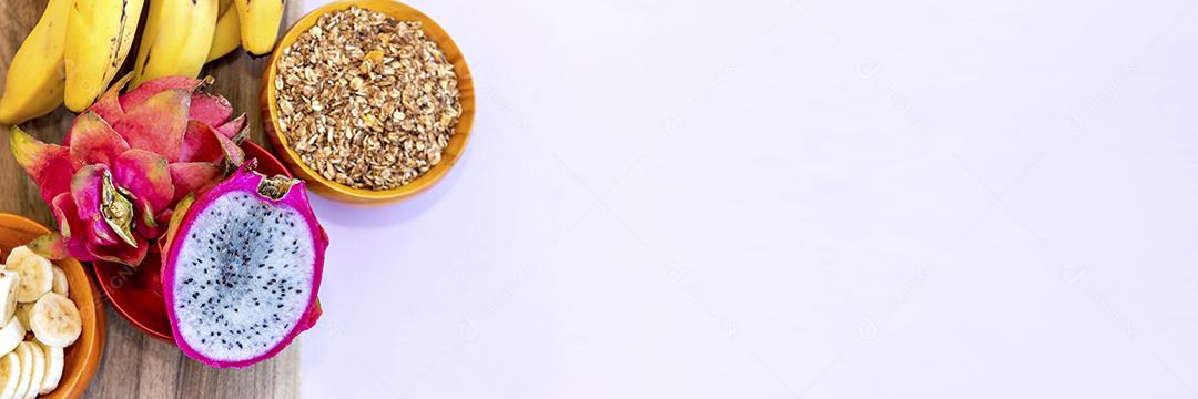 Prato com bananas fatiadas, granola e pitaya cortadas ao meio Vista superior formato ao ar livre