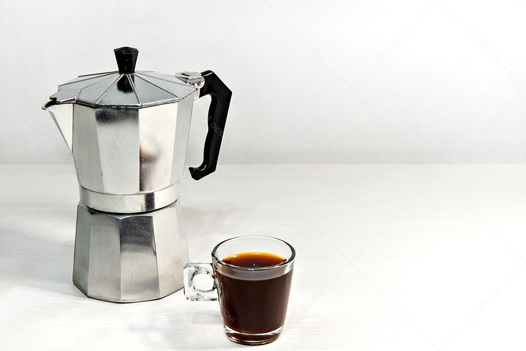 Italian coffee maker with espresso on white wooden table.