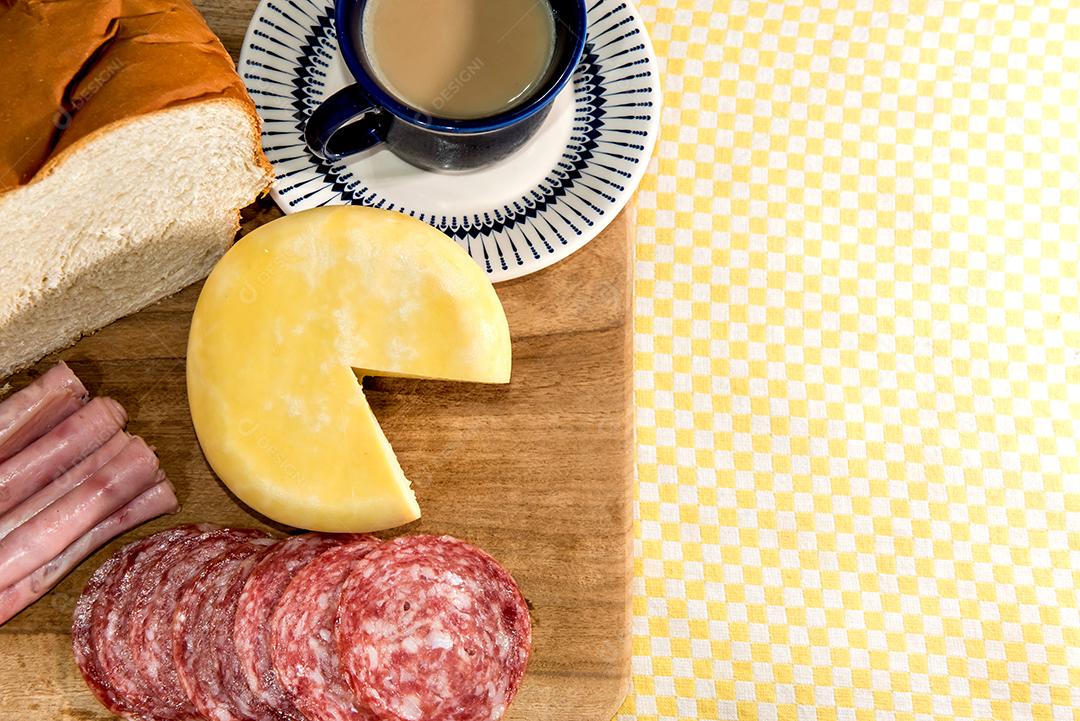 Café da manhã colonial servido com pão, queijo, presunto e salame