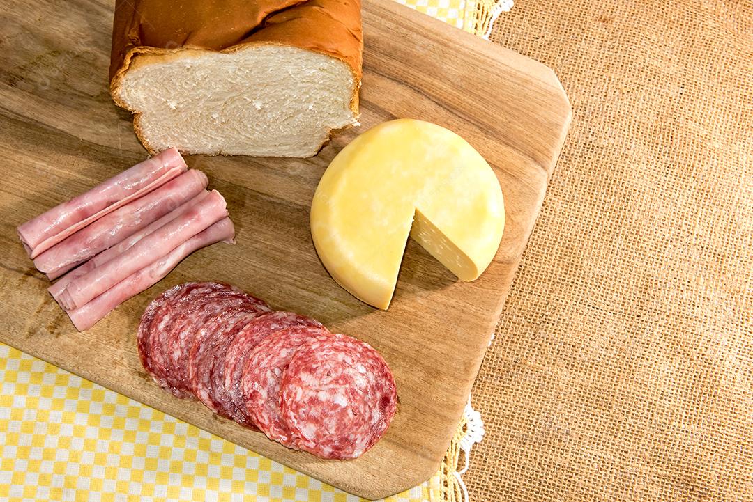 Café da manhã colonial servido com pão, queijo, presunto e salame