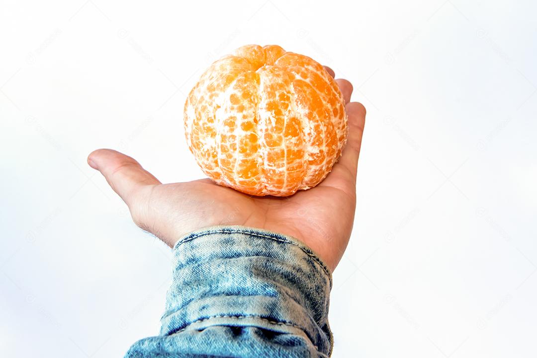 Mão segurando bergamota em fundo branco.