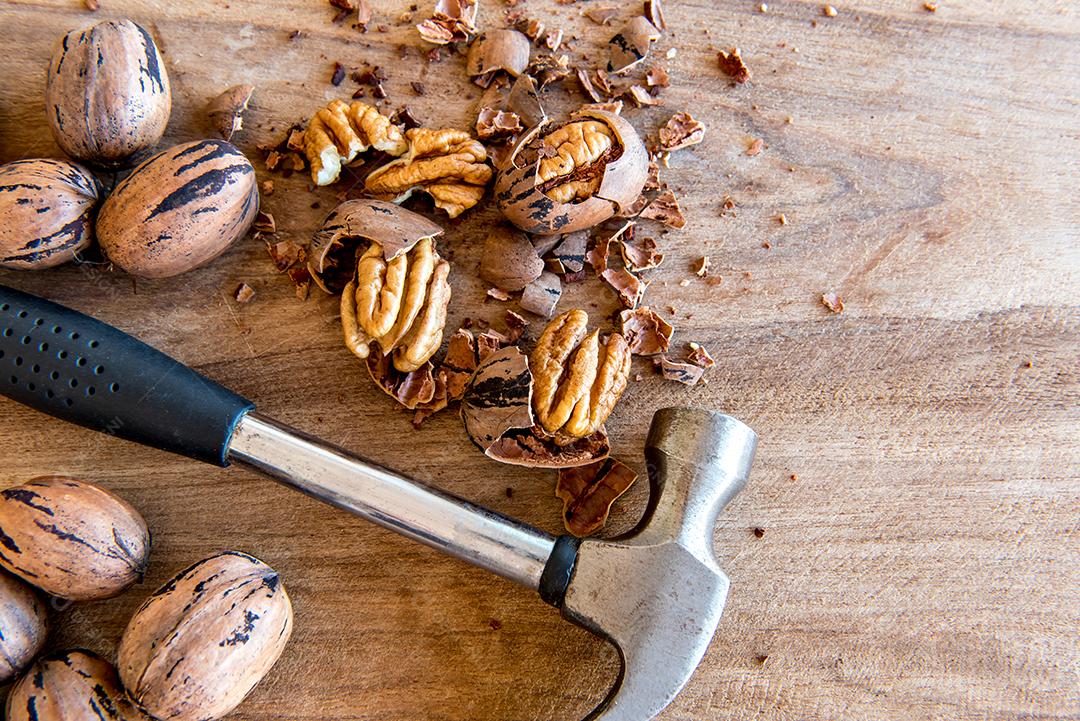 Quebre as nozes pecan com um martelo. Vista do topo.