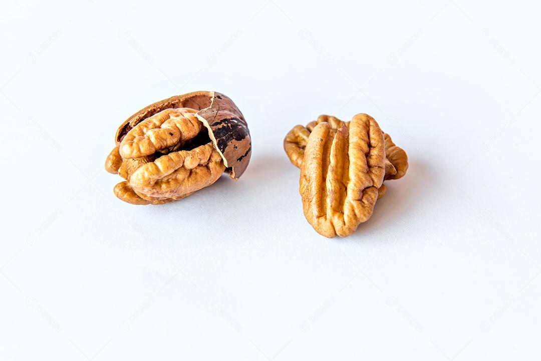 Nozes pecan descascadas em fundo branco.