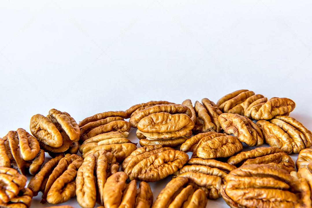 Nozes pecan descascadas em fundo branco.