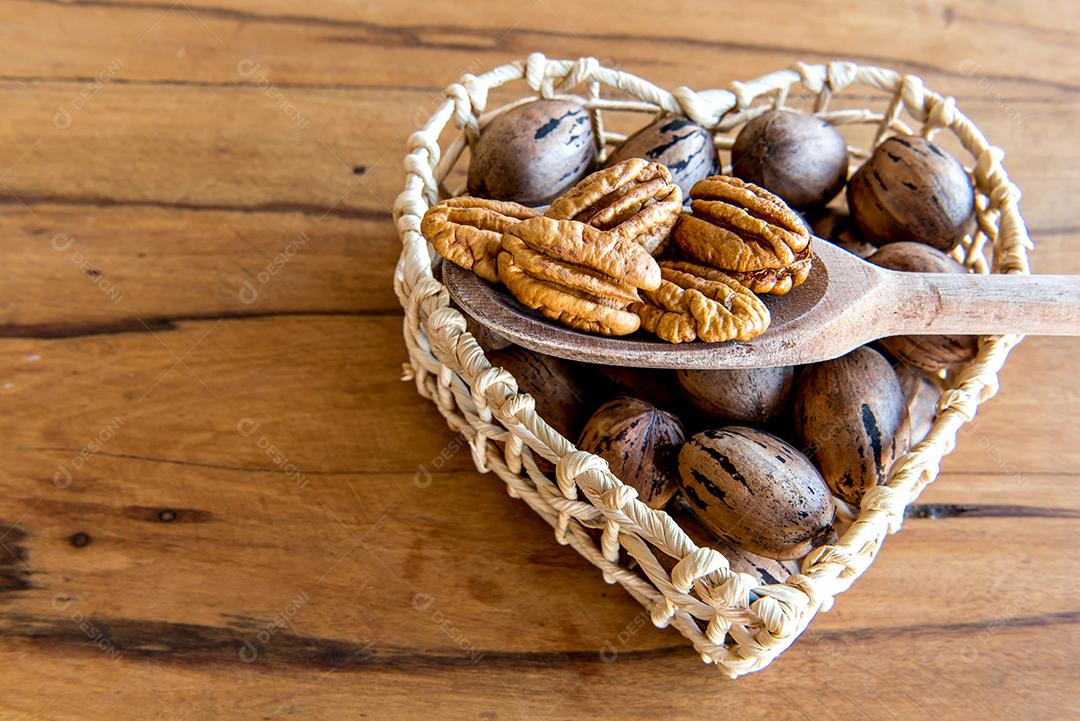 Nozes pecan descascadas em fundo de madeira.