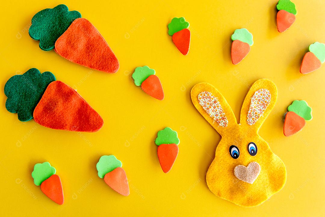 Decoração de páscoa, cenouras de páscoa e coelhinho em fundo amarelo