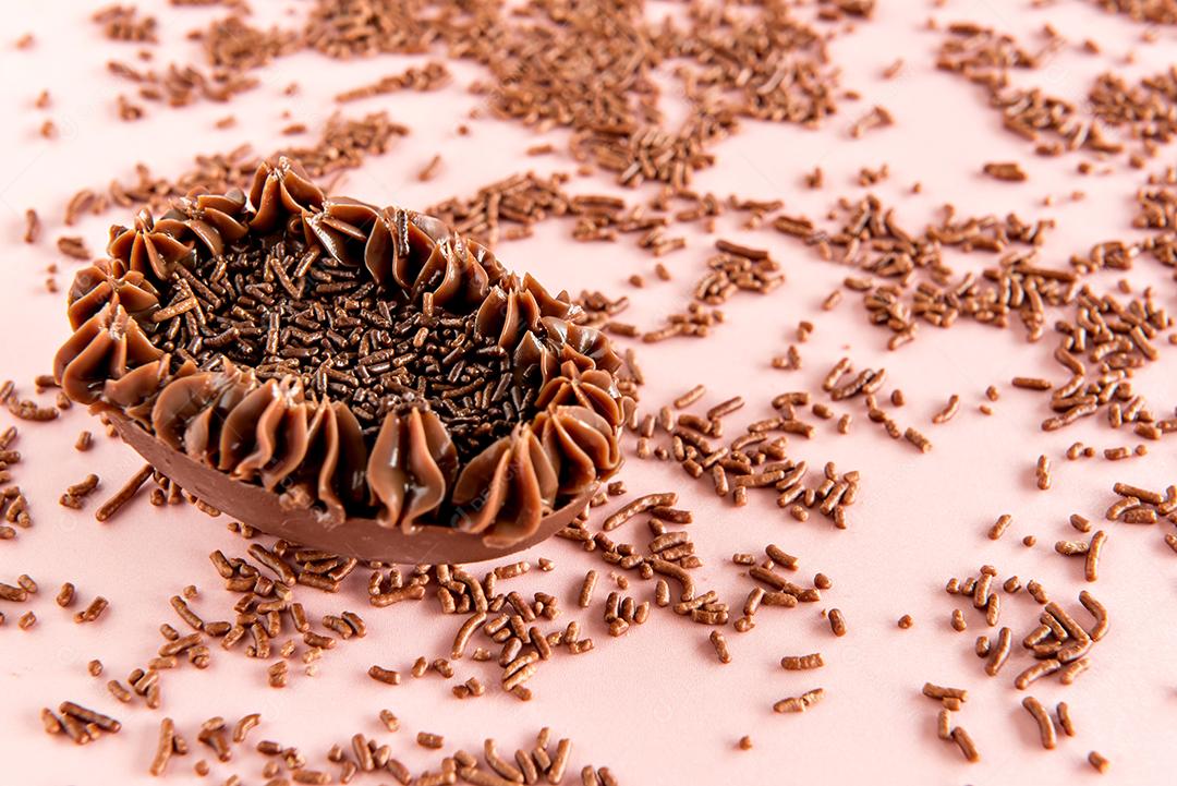 ovo de páscoa cheio de chocolate no fundo rosa com granulado