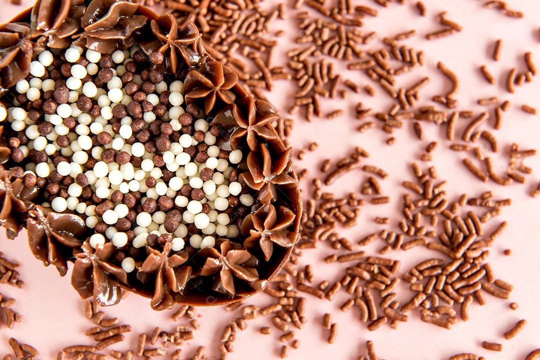 ovo de páscoa cheio de chocolate no fundo rosa com granulado