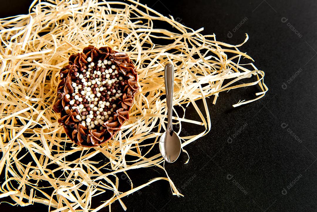 ovo de páscoa cheio de chocolate em fundo preto, colher de páscoa