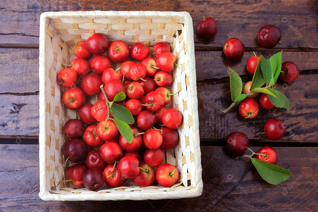 Acerola cereja crua, fresca, caixa na mesa de madeira rústica, frutas antioxidantes. Vitamina C alta