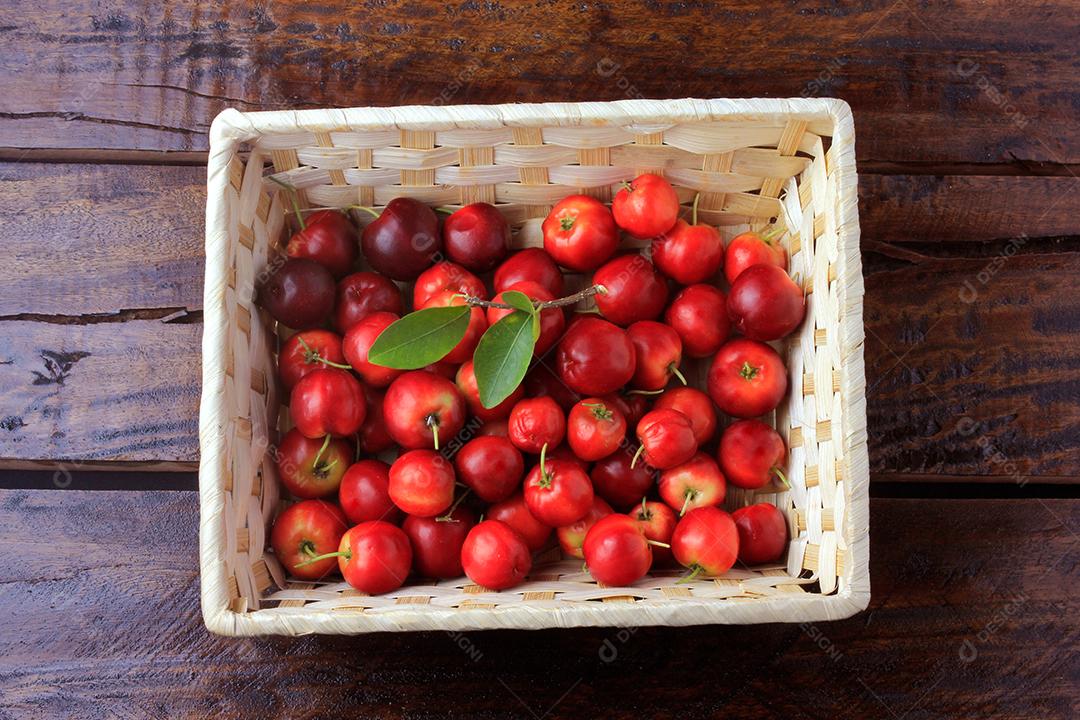 Acerola cereja crua, fresca, caixa na mesa de madeira rústica, frutas antioxidantes. Vitamina C alta