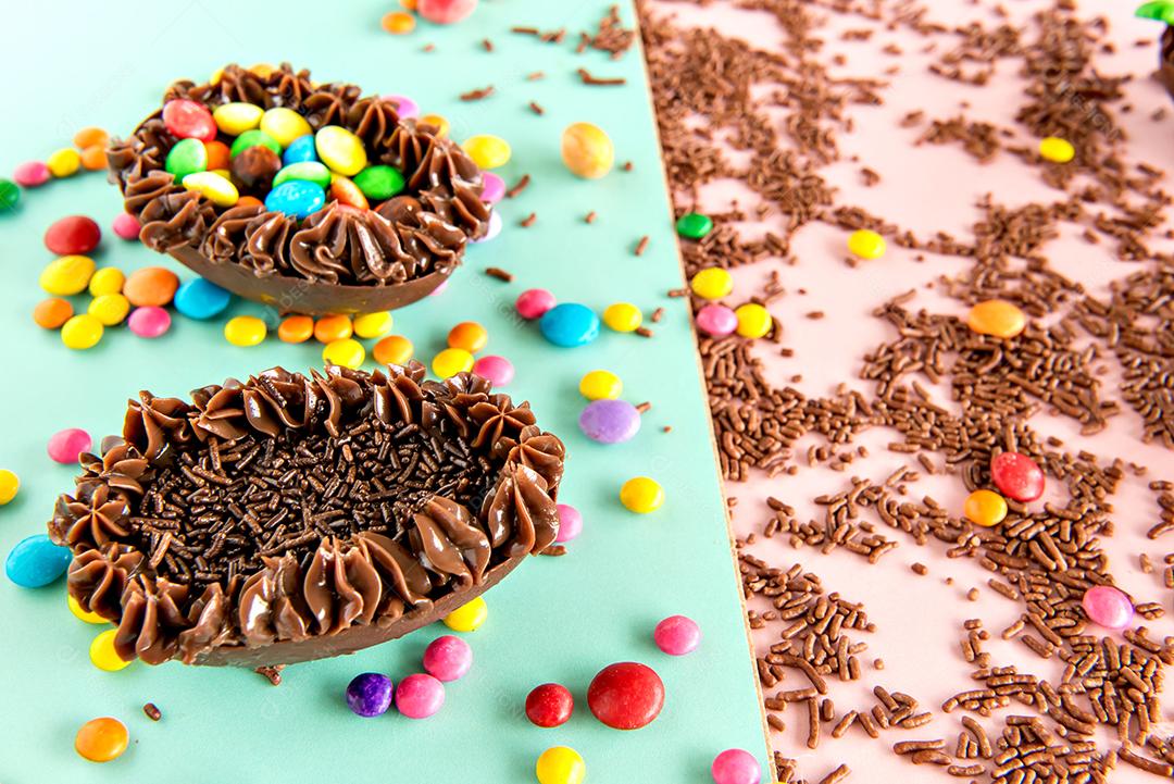 Ovos de Páscoa cheios de chocolate em um fundo colorido com granulado e confete