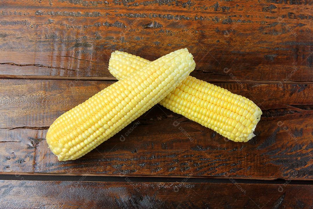 espiga de milho cru, colhida da plantação, na mesa de madeira rústica. espaço para texto