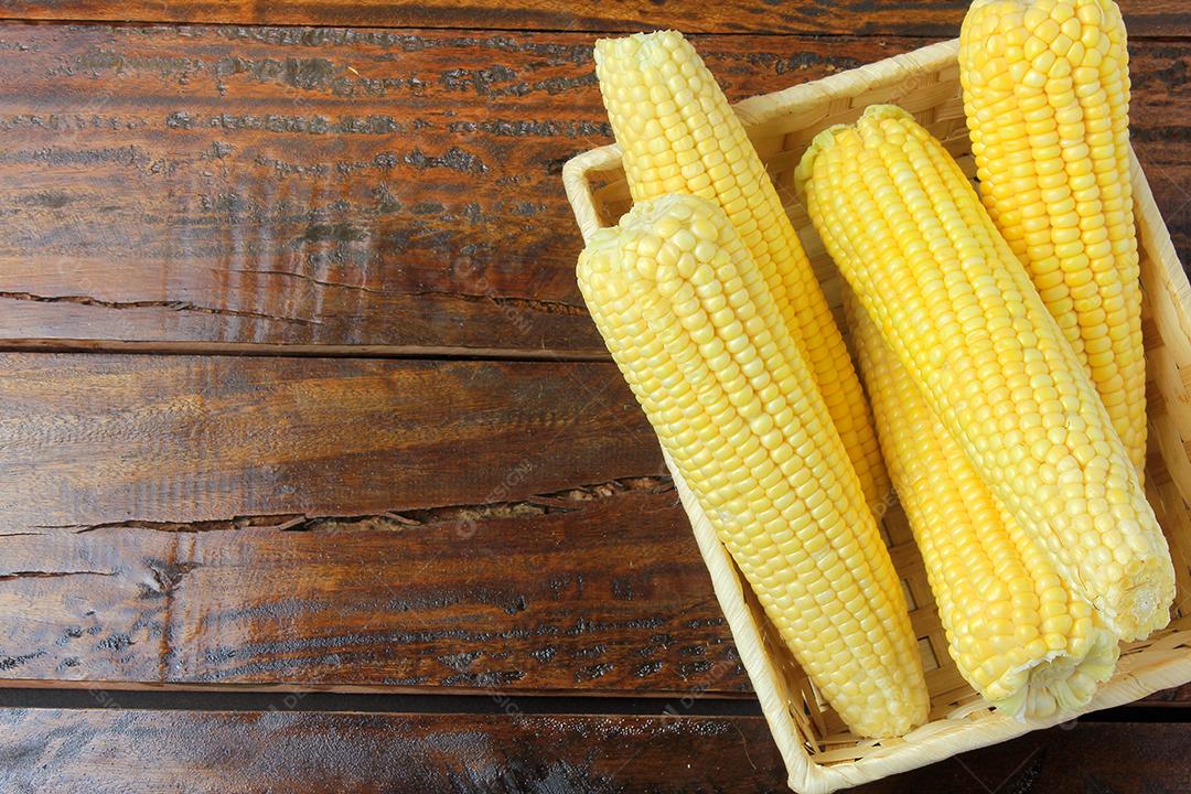 espiga de milho cru, dentro da cesta, colhida da plantação, na mesa de madeira rústica. espaço para texto. Vista do topo