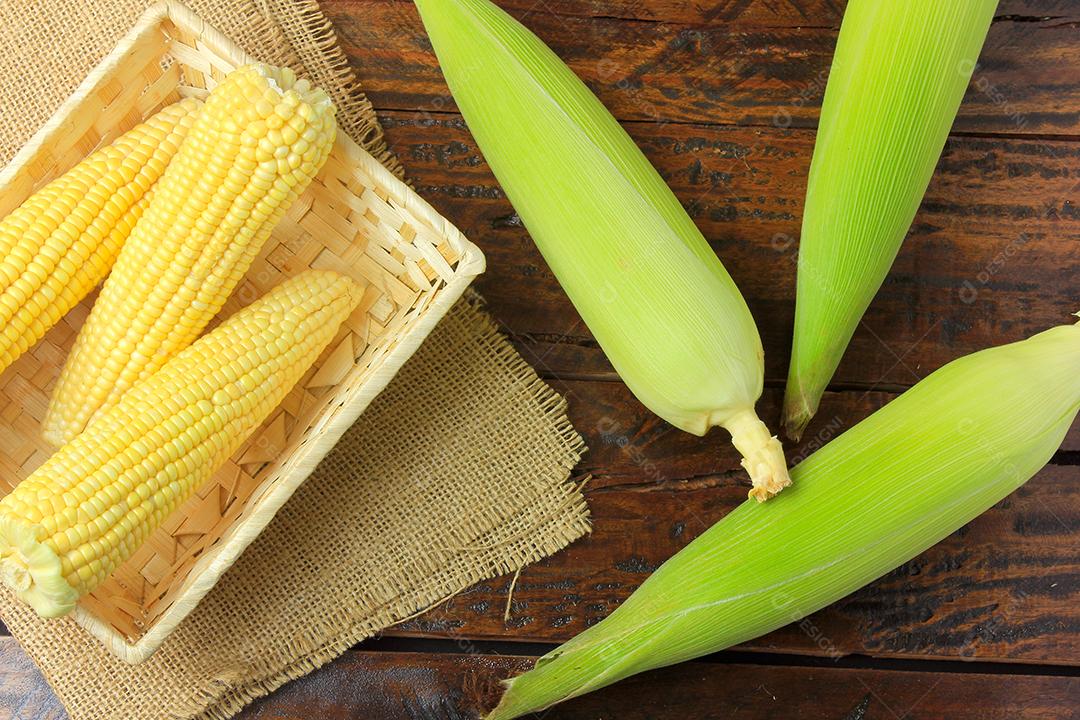 espiga de milho cru, dentro da cesta, colhida da plantação, na mesa de madeira rústica. espaço para texto. Vista do topo