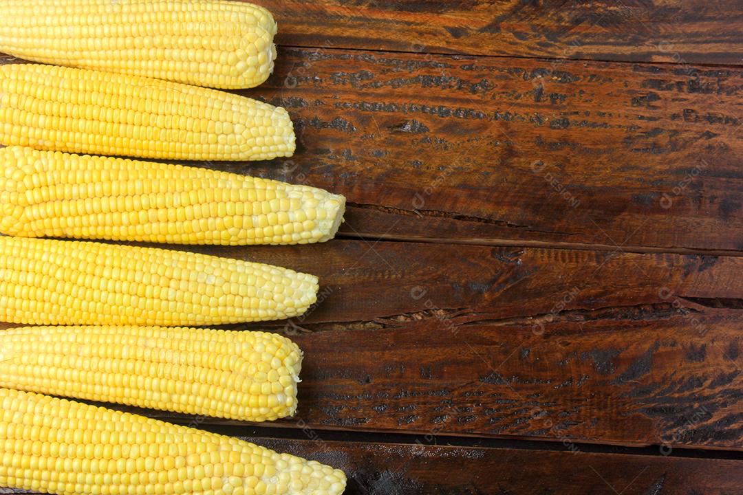 espiga de milho cru, colhida da plantação, na mesa de madeira rústica
