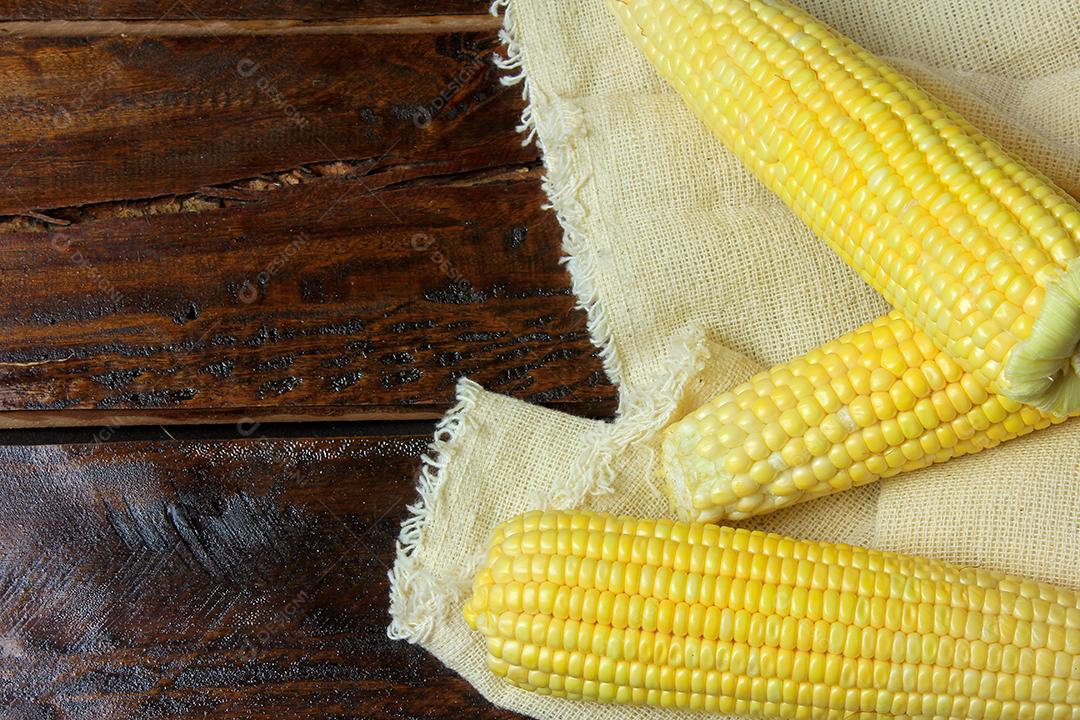 espiga de milho cru, em tecido rústico na mesa de madeira rústica. espaço para texto. Vista do topo