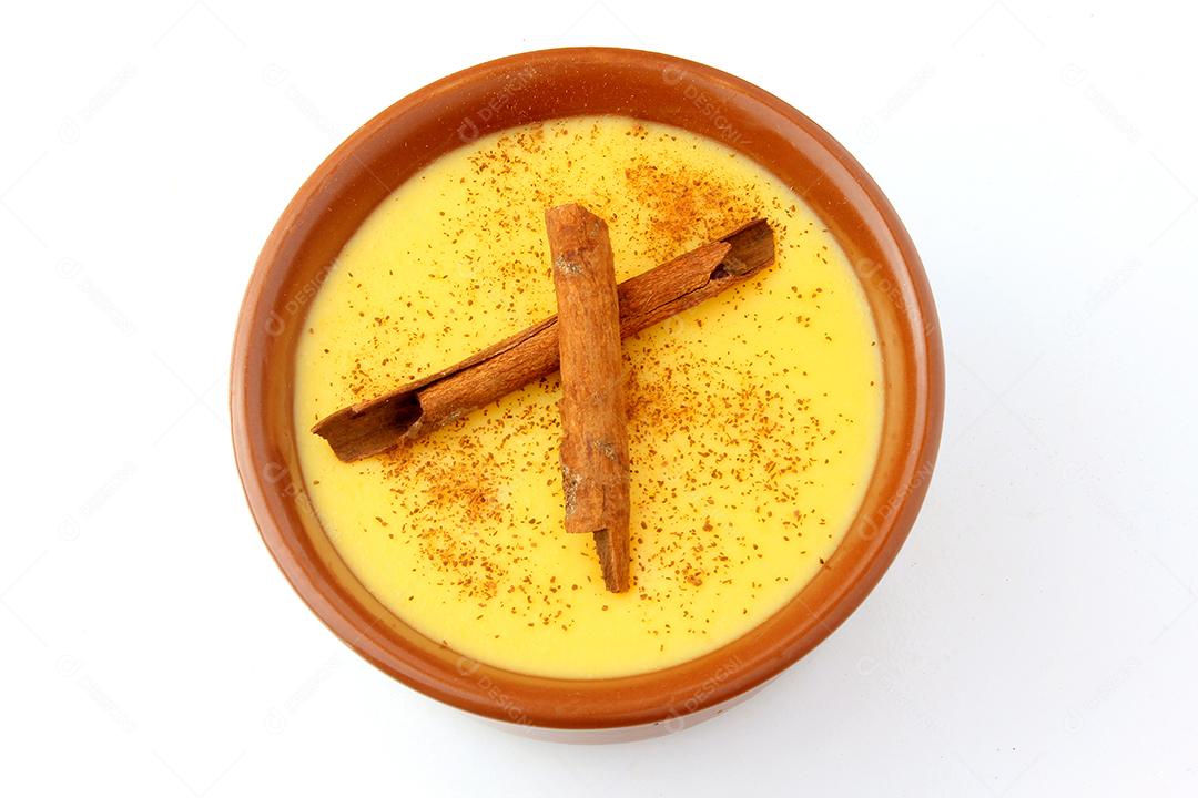 Curau, creme de milho doce e sobremesa típica da culinária brasileira, com canela colocada em tigela de cerâmica sobre fundo branco