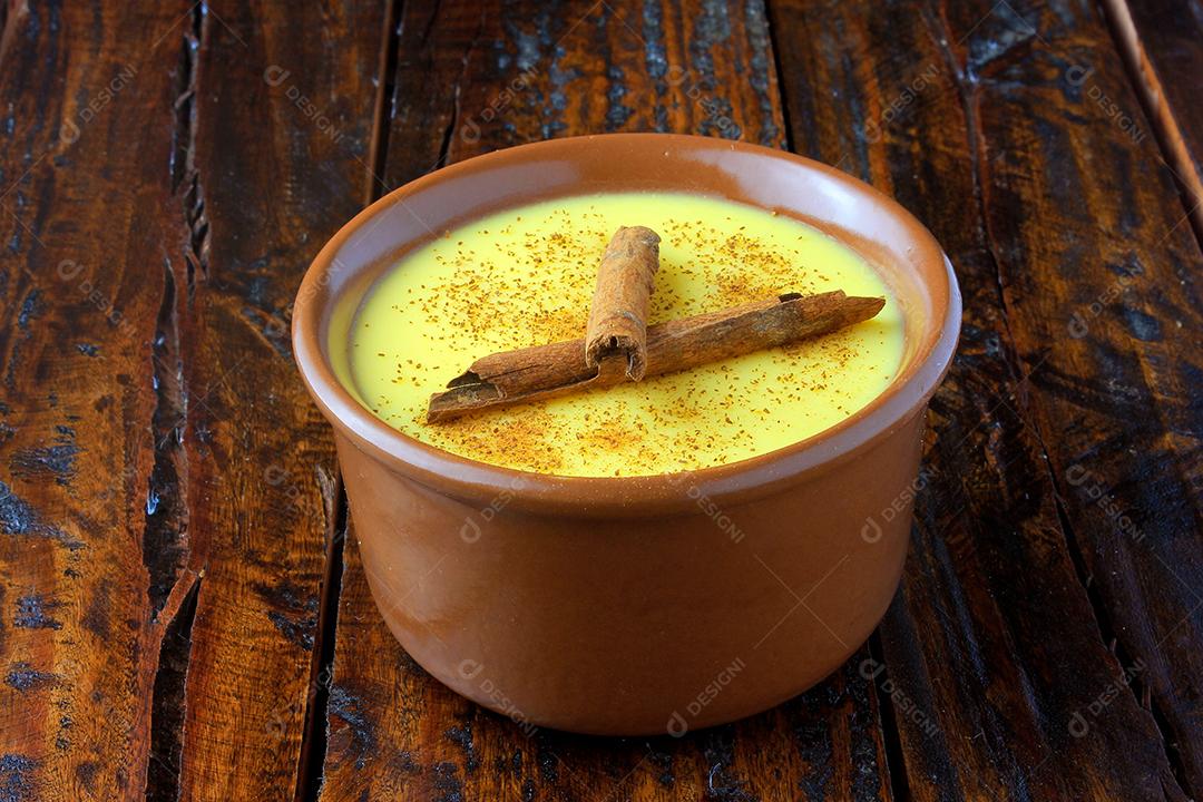 Curau, creme de milho doce e sobremesa típica da culinária brasileira, com canela colocada em tigela de cerâmica na mesa de madeira