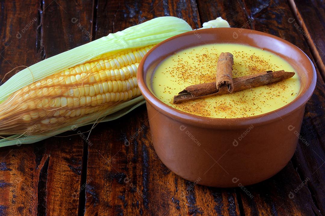 Curau, creme de milho doce e sobremesa típica da culinária brasileira, com canela colocada em tigela de cerâmica na mesa de madeira