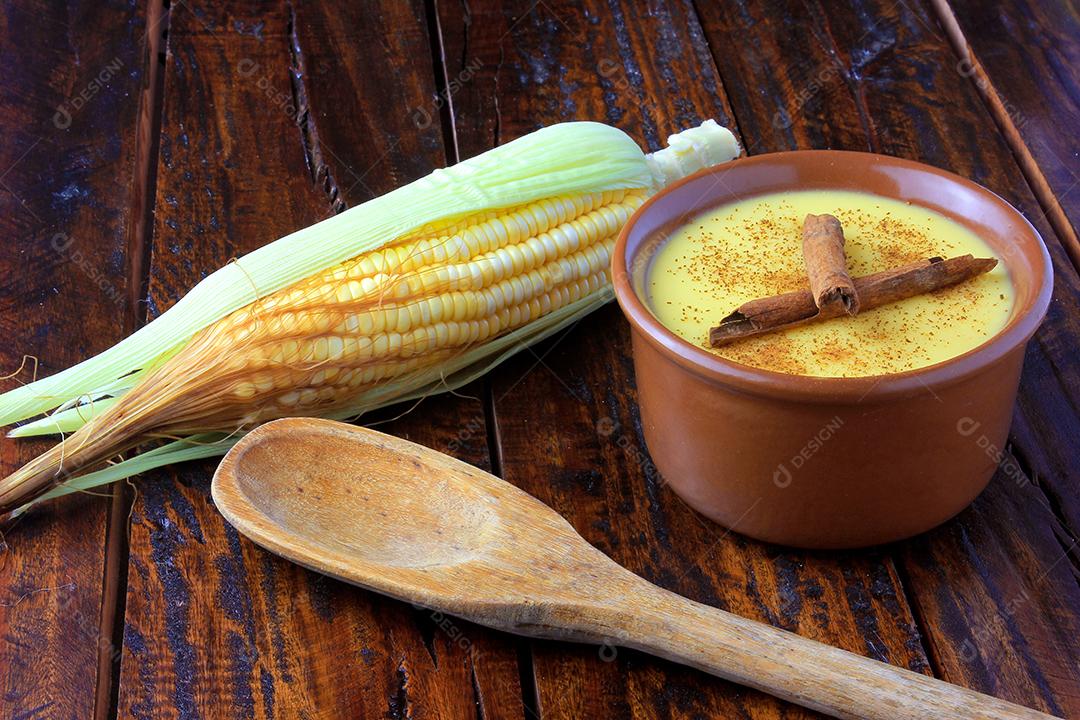 Curau, creme de milho doce e sobremesa típica da culinária brasileira, com canela colocada em tigela de cerâmica na mesa de madeira