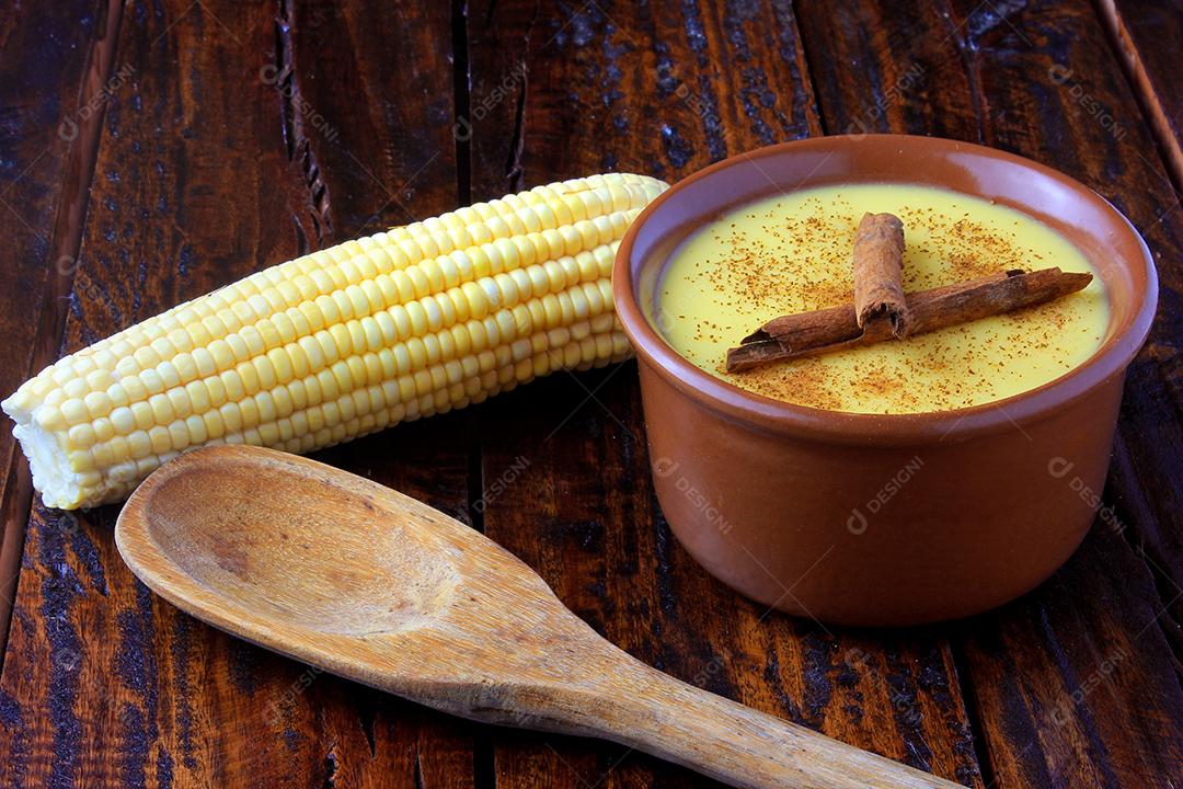 Curau, creme de milho doce e sobremesa típica da culinária brasileira, com canela colocada em tigela de cerâmica na mesa de madeira